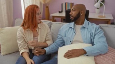 Irklar arası bir çift el ele tutuşup rahat bir evde, bir kanepede sohbet ediyorlar. İçleri pastel renklerle kaplı.