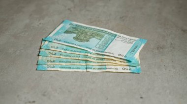 Hintli 50 rupilik banknotlar somut bir yüzeye yayılarak, paranın detaylarını ve dokusunu vurguluyor..
