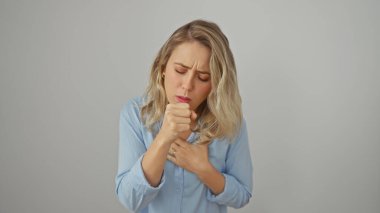 Mavi gömlekli genç bir kadın beyaz bir arka plana doğru öksürüyor.