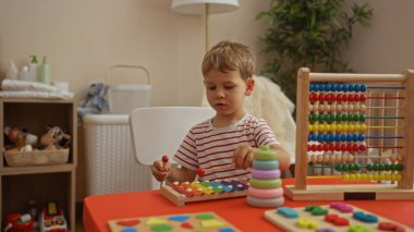 Çocukluk anılarını gözler önüne seren parlak bir anaokulunda eğitici oyuncaklarla oynayan küçük çocuk.