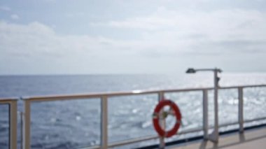 Bir yolcu gemisinin balkonundan bulanık deniz manzarası, gün ışığında parlak bokeh efektiyle çözülmüş korkulukları ve okyanus ufkunu vurguluyor..