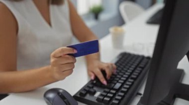 Bir ofis ortamında bilgisayar kullanırken kredi kartı tutan ve gülümseyen, online alışveriş veya ödeme işlemlerini resmeden bir kadın