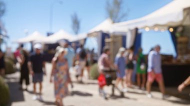 Güneşli Mallorca 'da arka planda çadırlarla açık hava pazarının keyfini çıkaran bulanık bir kalabalık.