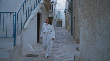 Genç bir İspanyol kadın polignano 'nun güzel, dar sokaklarında yürüyor. Puglia, İtalya' da bir kısrak. Mavi merdivenlerin yanındaki tarihi İtalyan mimarisine hayran..