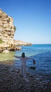 Polignano 'da genç bir İspanyol kadın bir kısrak, puglia, İtalya sahilde kayalık kayalıklarla ve açık mavi denizle güzel bir günün tadını çıkarıyor..
