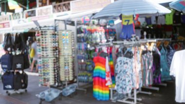 Değişik yaz elbiseleri, güneş gözlükleri, sırt çantaları ve çözülmüş bir arka planı olan bulanık bir dükkan.