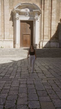 İspanya 'nın Puglia şehrinin eski sokaklarında yürüyen genç bir İspanyol kadın. Arka planda güzel tarihi bir bina var..