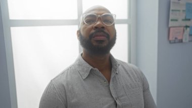 Ofisin içinde sakallı ve gözlüklü yakışıklı Afro-Amerikan bir adam.