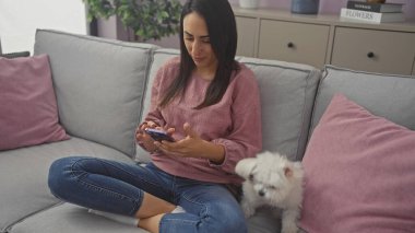 Beyaz Bizon Malta 'sının yanında rahat bir oturma odasında otururken telefonda mesaj atan İspanyol kadın..