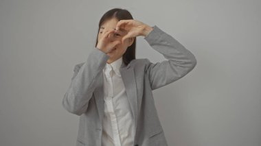 Profesyonel kıyafetli Asyalı bir kadın beyaz arka planda parmaklarıyla kalp şekli oluşturur.