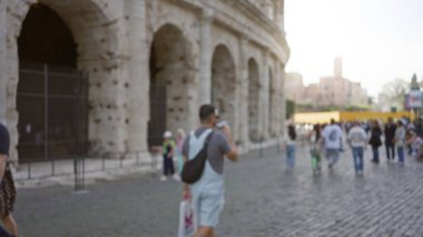 Roma 'daki ikonik kolezyumun yanında yürüyen bulanık turistler Bokeh etkisi altında İtalya' nın hareketli antik Roma simgesinin hareketli atmosferini yaratıyor..