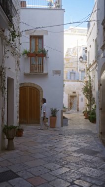Genç İspanyol kadın polignano 'nun büyüleyici sokaklarında geziniyor. Puglia, İtalya, Avrupa' da bir kısrak. Etrafı kırsal ve taştan binalarla çevrili..