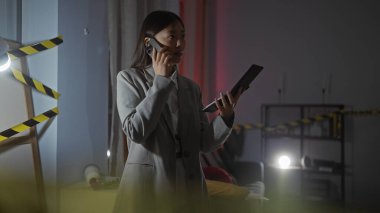 Telefondaki Asyalı kadın, loş aydınlatılmış bir suç mahallinde elinde not defteri tutuyordu..