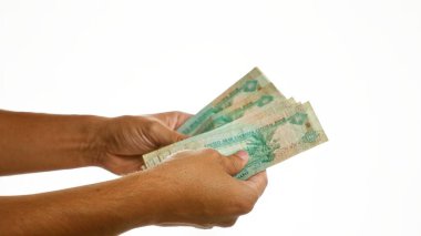 İzole edilmiş beyaz bir arkaplan üzerinde birden fazla uae dirham banknotları tutan eller, Birleşik Arap Emirlikleri para birimini canlı olarak gösteriyor.