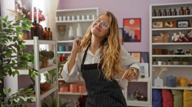 Arka planda çeşitli bitkiler ve dekoratif eşyalar olan güzel dekore edilmiş bir ev dekorasyonunda neşeyle dans eden genç bir kadın.