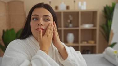 Kaplıcada spa tedavisi gören genç bir kadın. Beyaz bir bornoz giyiyor. Huzurlu bir sağlık merkezi içiyle çevrili..