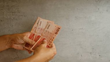 Eller beton bir arka planda Tayvan dolarlarını tutuyor