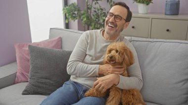 Neşeli, orta yaşlı, İspanyol bir adam sıcak bir oturma odasında kanişi kucaklıyor..