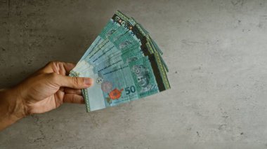 Malezya ringgit banknotlarını beton bir arka planda tutan, Malezya 'da bir adamın parmaklarını yakalayan,.