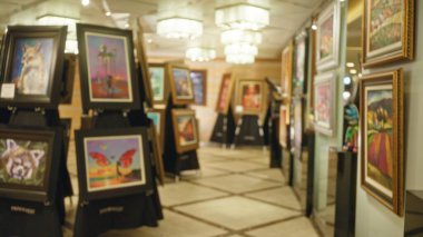 Renkli resimler ve zarif ışıklarla dolu bir sanat galerisinin bulanık görüntüsü sanat meraklıları için mükemmel sakin ve sofistike bir atmosfer yaratıyor..