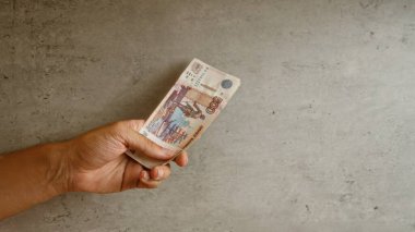 Rusya 'daki finansal temaları vurgulayarak, beton duvar zeminine karşı el ele tutuşan Rus rublesi