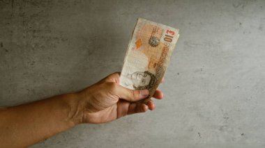 Beton bir zemine karşı on İngiliz poundu tutuyor, para birimini kentsel bir ortamda vurguluyor