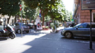 Güneşli bir Roma caddesinde Bokeh etkisi. Odaklanamayan arabalar ve bulanık yayalar, büyüleyici İtalyan eski kasaba atmosferini ön plana çıkarıyor..