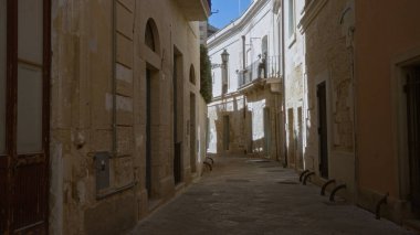 Tarihi Lecce, Puglia, İtalya 'da dar taştan bir cadde. Yol boyunca uzanan büyüleyici eski binalarla güneş ışığıyla yıkanmış..
