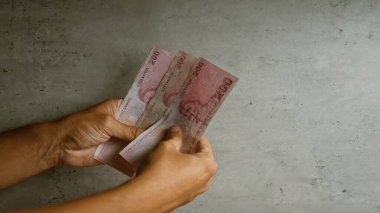 Türk liretlerini beton bir zemine dayayan eller, para birimi ve dokusunu vurguluyor