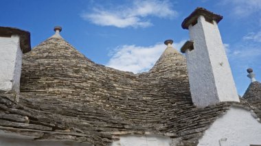 Alberobello, Puglia, İtalya 'daki geleneksel koni çatılı evler, bu Avrupa' nın pitoresk kasabasında eşsiz bir mimari sergilenen canlı mavi gökyüzüne karşı..