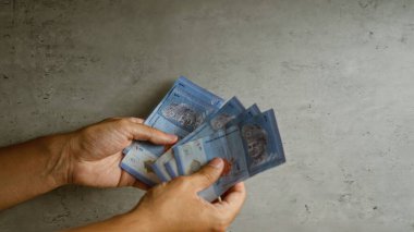 Elleri beton bir arka planda Malezya halkasını tutuyor