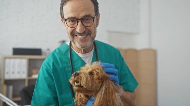 Kliniğin içinde kaniş tutan gülümseyen bir veteriner..