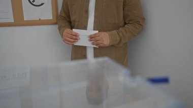 Seçim sırasında kapalı bir sandık merkezinde oy kullanan genç bir adam.