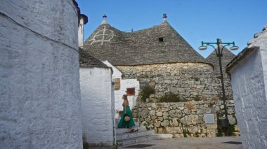 Genç İspanyol bir kadın, Avrupa 'nın açık gökyüzünün altında, eski Alberobello, Puglia, İtalya' da tarihi trulli evlerle dolu, büyüleyici bir cadde boyunca yürüyor..