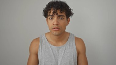 Kolsuz tişörtlü genç bir İspanyol 'un portresi. Beyaz bir arka planda izole edilmiş, dalgın görünüyor..