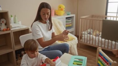 Oğlu ve kızı olan bir kadın rahat yatak odasında birlikte oynuyor. Oyuncak ve beşikte, evde sevgi dolu bir aile anını tasvir ediyor..