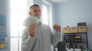 Ofisteki genç adam elinde dolarlarla mutlu ve başarılı hissediyor.