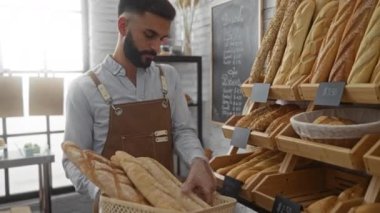 Odadaki fırında ekmek toplayan sakallı genç bir adam.