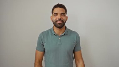 Ayakta duran ve gülümseyen mutlu bir İspanyol genç parmak ve izole beyaz bir arka plan üzerinde el ile kenarı işaret ediyor.