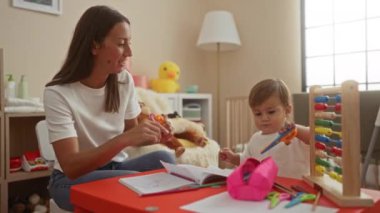 Yatak odasında oyuncaklarla küçük çocuklara öğretmenlik yapan bir kadın. Öğrenme etkinliği, bağ ve aşk gösterisi yapıyor..