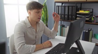 Ofisteki genç bir adam, arka planda bitkiler ve organize dosyalar olan bir video görüşmesine katılmış..