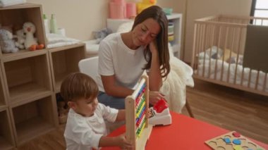 Kadın küçük oğluyla rahat bir yatak odasında iletişim kuruyor, aile bağlarını güçlendiriyor ve abaküs ile öğreniyor, ev sıcaklığını ve sevgiyi ön plana çıkarıyor..