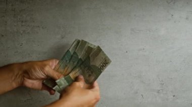 Elleri sayma Endonezya rupia para birimi beton bir arka plan karşı