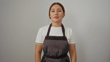 Önlüklü genç İspanyol kadın mutlu bir gülümseme, parmak ve el hareketleriyle yalıtılmış beyaz arka planı işaret ediyor.