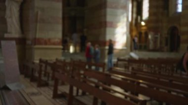 Ahşap sıralar ve heykel ile loş aydınlatılmış bir kilise iç mekanındaki insanların bulanık görüntüsü, sakin bir atmosfer için odağını kaybetmiş dini bir ortam ve hafif ışıklandırma içeriyor..