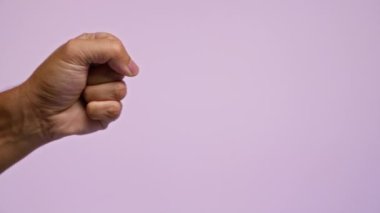Adamın yumruğu ve eli pembe bir arka plana karşı güç ve uzlaşma ifadelerini gösteriyor.