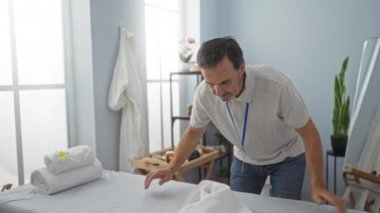 Huzurlu bir klinikte havlu düzenleyen adam, sağlık ve bakım üzerine odaklı profesyonel bir terapi ortamı öneriyor..