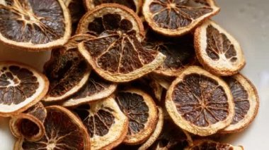 Kurumuş portakal dilimleri bir kasede istiflenir. Karmaşık dokularının ve susuz durumlarının yakın görüntüsünü sunar.