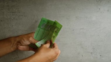 Beton bir duvara karşı Malezya halkasını sayan kişi, Malezya 'da elleri, parmakları ve para birimini gösteriyor