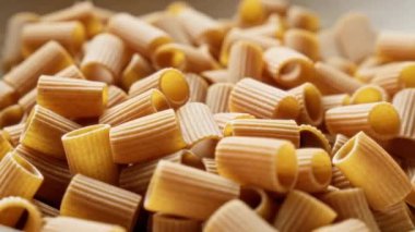Pişmemiş rigatoni makarnasının yakın çekimi, İtalyan mutfağını vurgulayan detaylı bir yemek fotoğrafında dokularını ve silindirik şekillerini gözler önüne seriyor.